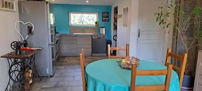 a kitchen with a blue table and chairs and a table and a kitchen at Gîte 