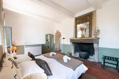 a bedroom with a large bed and a fireplace at Au Ralenti du Lierre in Beaumettes