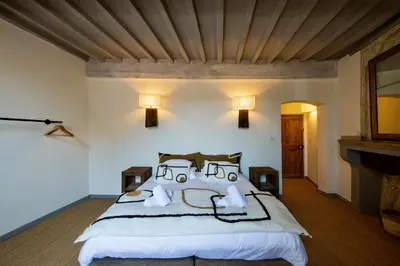a bedroom with a large white bed and a fireplace at Au Ralenti du Lierre in Beaumettes