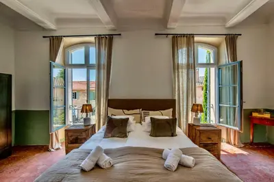 a bedroom with a large bed with windows at Au Ralenti du Lierre in Beaumettes
