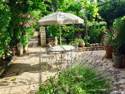 a table and chairs under an umbrella in a garden at le vieux pont in Carpentras
