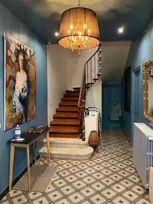a hallway with a staircase with a painting and a chandelier at La maison Gerval in Bédoin