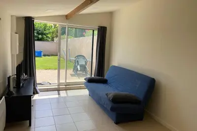 a blue couch in a living room with a sliding glass door at Loft 21 m² pouvant accueillir 4 personnes in Monteux
