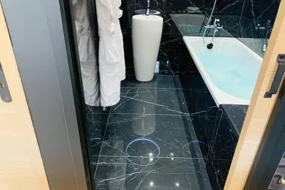 a bathroom with a black tiled floor and a white sink at Suite Le CEZANNE in Aix-en-Provence