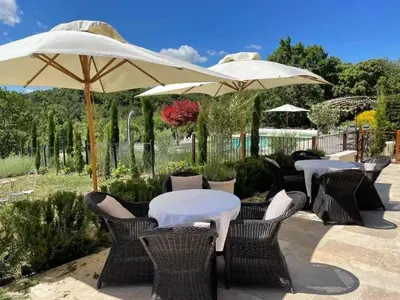 a group of tables and chairs with umbrellas at Bastide provençale à Murs, coeur du Lubéron in Murs