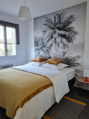 a bedroom with a large bed with a palm tree mural at L'Isle Ô Jardin in LʼIsle-sur-la-Sorgue