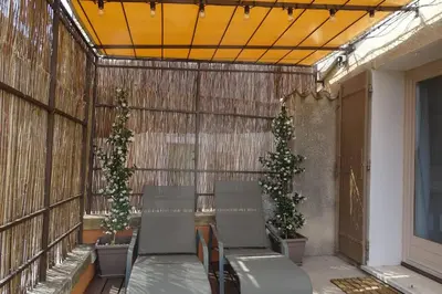 a patio with two chairs and two trees on it at La maison de Gaston au cœur du Luberon in Villars