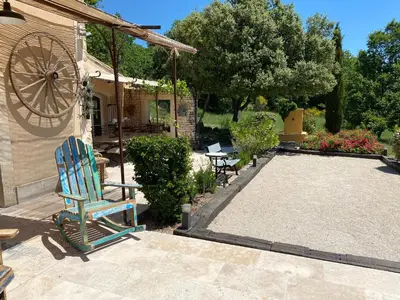 a yard with a blue chair and a house at Location bastide provencale Luberon in Murs