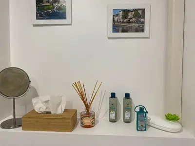 a white counter with two bottles of soap and a lamp at Côté Court in LʼIsle-sur-la-Sorgue