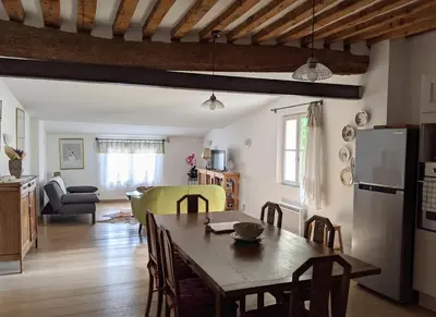 a kitchen and living room with a wooden table and a dining room at LOlivier sur le Toit in LʼIsle-sur-la-Sorgue