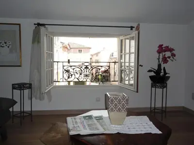 a living room with a window and a table with a newspaper at LOlivier sur le Toit in LʼIsle-sur-la-Sorgue
