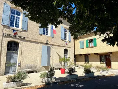 a building with blue windows and plants in front of it at A l’ombre du géant de Provence in Mormoiron