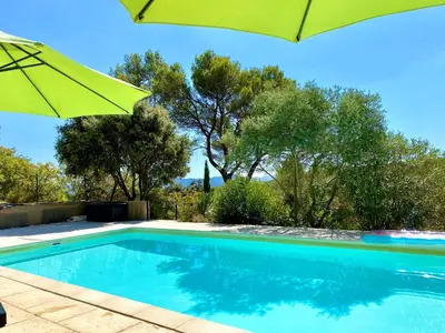 a swimming pool with a green umbrella and trees at Mas d'Olea - heated swimming pool - airco - 14pers in Lauris