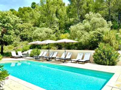 a swimming pool with lounge chairs and umbrellas next to at Mas d'Olea - heated swimming pool - airco - 14pers in Lauris