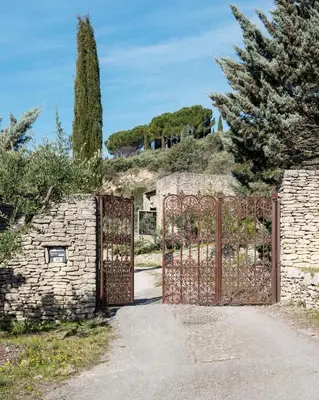 an entrance to a stone building with an iron gate at l'Atelier des Milles Roches in Gordes
