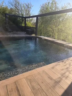 a large swimming pool with a wooden deck at Un petit coin de Bali avec SPA et piscine privés in Carpentras