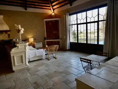 a living room with a bed and a large window at Le Pool House - Private Jacuzzi - Mas des Sous Bois in Ventabren