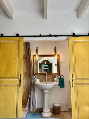 a bedroom with a bed and a shelf with a microwave at LE PETIT JARDIN ... in LʼIsle-sur-la-Sorgue