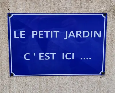 a blue street sign on the side of a building at LE PETIT JARDIN ... in LʼIsle-sur-la-Sorgue
