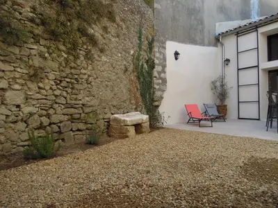 a patio with a stone wall and a red chair at La Bourgade in Céreste