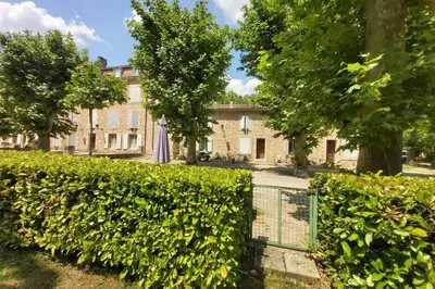 a hedge in front of a building with an umbrella at Appartement de charme au calme avec piscine, au pied du Colorado provençal, cœur du Luberon in Rustrel