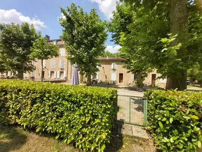 a hedge in front of a building with an umbrella at Appartement de charme au calme avec piscine, au pied du Colorado provençal, cœur du Luberon in Rustrel