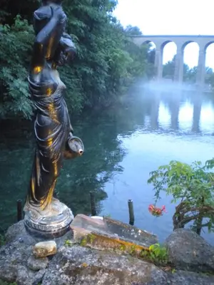 a statue of a woman standing next to a river at Appartement à FONTAINE DE VAUCLUSE in Fontaine-de-Vaucluse
