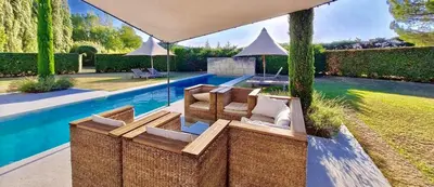 a backyard with a swimming pool and a patio with chairs and an umbrella at LASUITE Domaine Bertuli, heated Pool, Aircon in Oppède