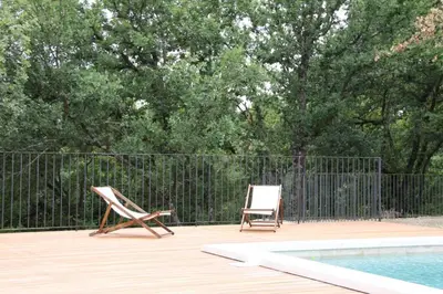 two chairs sitting on a deck next to a pool at Mas de la Chêneraie Blanche, Maison de vacances avec piscine en Luberon in Roussillon