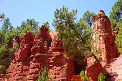a group of red rocks with trees in the background at Mas de la Chêneraie Blanche, Maison de vacances avec piscine en Luberon in Roussillon