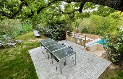 a table and chairs in a backyard with a pool at Maison & Jardin Coeur Luberon classé 4 étoiles in Peypin-dʼAigues