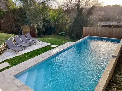 a swimming pool in a yard with two lawn chairs next to it at Maison & Jardin Coeur Luberon classé 4 étoiles in Peypin-dʼAigues