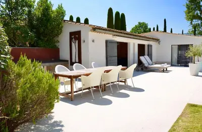 a patio with a wooden table and white chairs at Les Cerisiers maison bertuli climatisé, Piscine chauffée, lit King size, classé 5 étoiles in Oppède