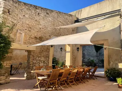 a patio with a table and chairs under a white umbrella at Villa Velleron - Bed and Breakfast in Velleron