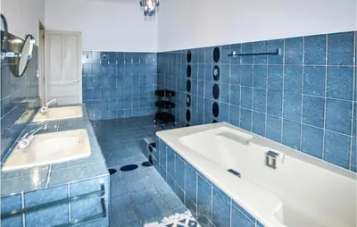 a blue tiled bathroom with a tub and a sink at 7 Bedroom Nice Home In Apt in Apt
