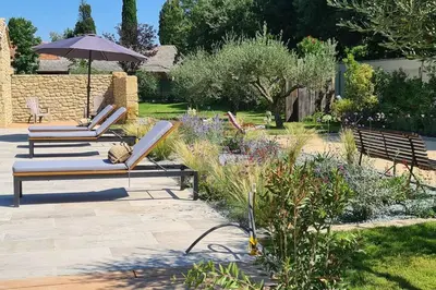 two lounge chairs and an umbrella in a garden at Le Cabanon de Nans. Gîte de charme en Provence. in Grans