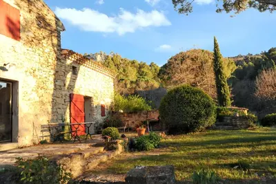 an old stone building with a red door in a yard at Villa élégante avec piscine privée à Ansouis, vues montagne in Ansouis