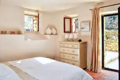 a bedroom with a bed and a dresser and a window at Villa élégante avec piscine privée à Ansouis, vues montagne in Ansouis