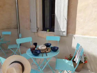 a patio with blue chairs and a table with bowls on it at MAISON BOURGUES in Lioux