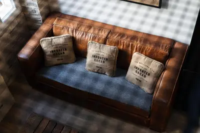a brown leather couch with two pillows on it at OPEN SKY Industry Hyper Centre Fontaine Moussue in Salon-de-Provence