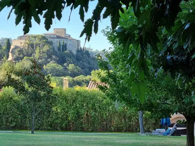 a park with a castle on top of a hill at Petit nid douillet en Luberon avec spa in Ansouis