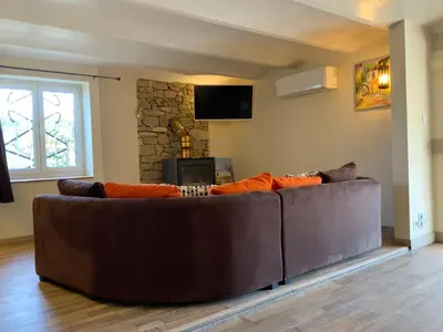 a brown couch in a living room with a tv at Au petit bonheur in LʼIsle-sur-la-Sorgue