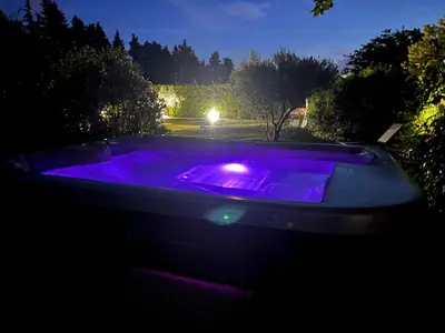 a jacuzzi tub with purple lights in the dark at Au petit bonheur in LʼIsle-sur-la-Sorgue
