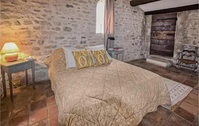 a bedroom with a bed and a table with a lamp at Awesome Home In Bonnieux With Sauna in Bonnieux