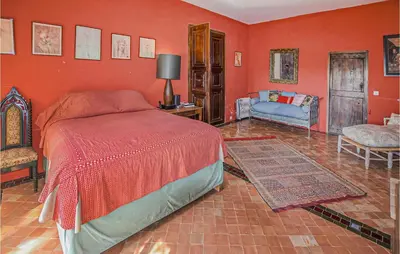a bedroom with red walls and a bed and a couch at Awesome Home In Bonnieux With Sauna in Bonnieux