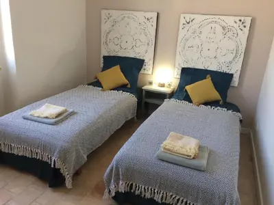 two beds in a room with blue and yellow pillows at Chambre d'hôte Mas de Silvacane in La Roque-dʼAnthéron
