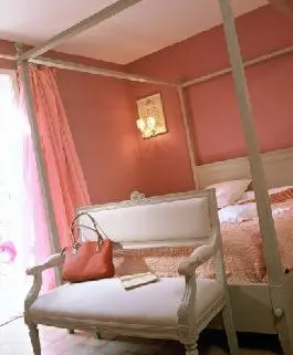 a red bedroom with a chair with a purse on it at Logis Hôtel restaurant des Pins in Bédoin