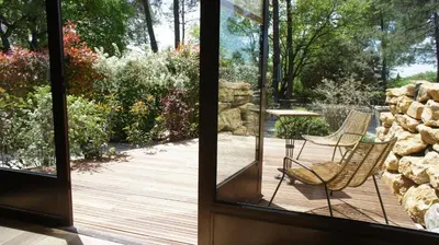 an open door to a deck with two chairs and a table at Logis Hôtel restaurant des Pins in Bédoin