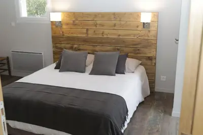 a bedroom with a white bed with a wooden headboard at Villa pleine campagne, piscine chauffée , Lubéron in Lacoste