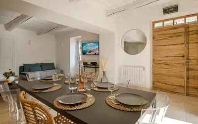 a dining room with a table and chairs and a living room at Le Mas des Sablières in Oppède